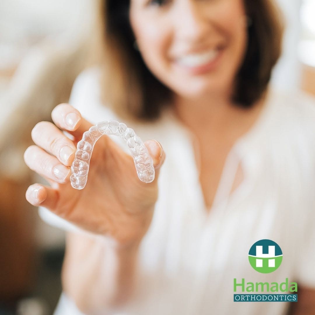 Dr. Allison Hamada holding a clear aligner tray at Hamada Orthodontics in the New Orleans area, the same Invisalign-style treatment she provides to patients