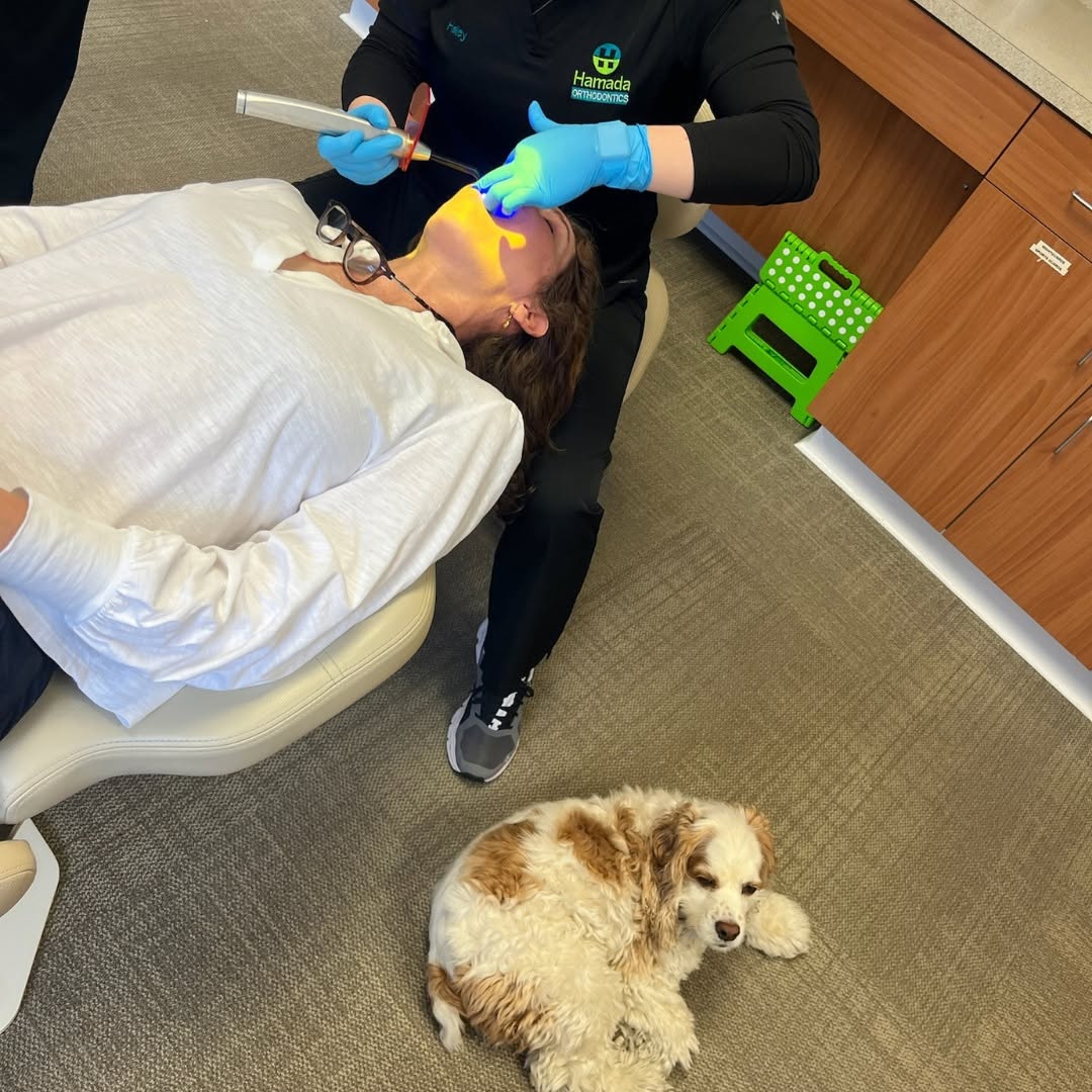 Dr. Hamada starting her own clear aligner treatment at Hamada Orthodontics in the New Orleans area, with office dog Daisy resting nearby